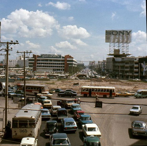 This picture was probably taken around 1975. The patch of green trees has been replaced with what will eventually become Siam Centre, there is noticeably more traffic, and the buses haven't changed.